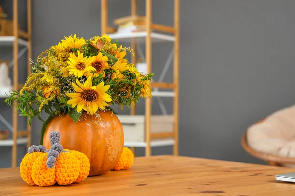 Pumpkins with autumn bouquet on table in living room, closeup
