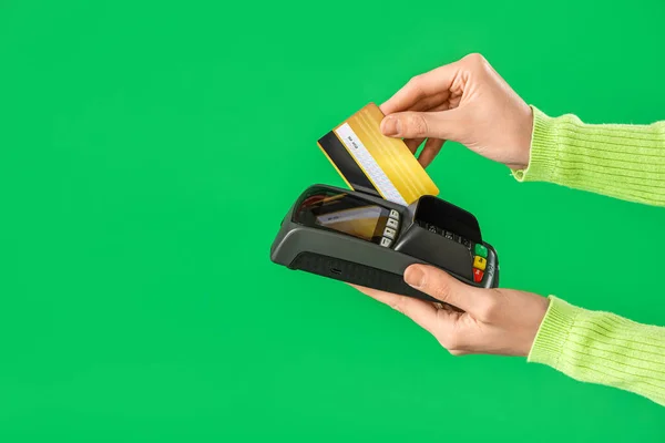 Young woman with credit card and payment terminal on green background, closeup