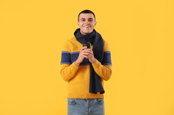 冬の服に黄色の背景にコーヒーを飲む若い男 — ストック写真