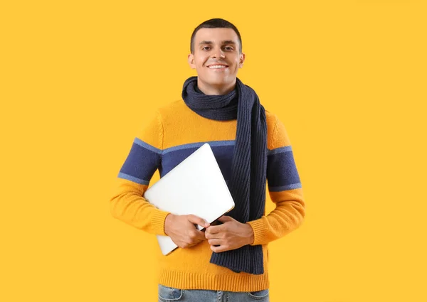 黄色の背景にラップトップと冬の服の若い男 — ストック写真