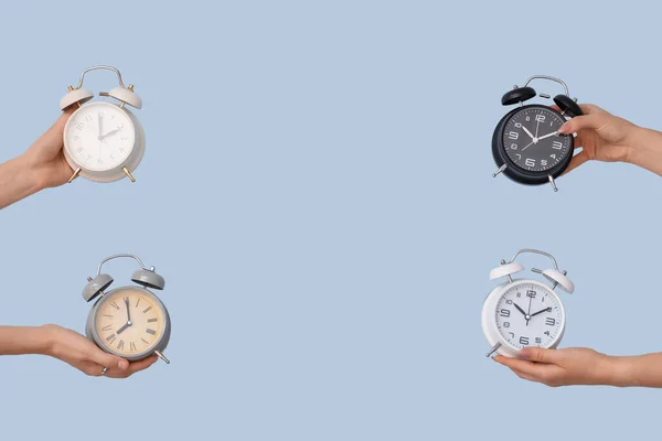 青い背景に異なる目覚まし時計を保持する手 — ストック写真
