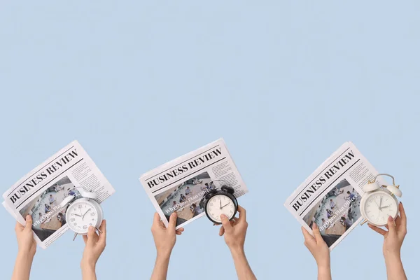 青い背景に異なる目覚まし時計や新聞を保持する手 — ストック写真