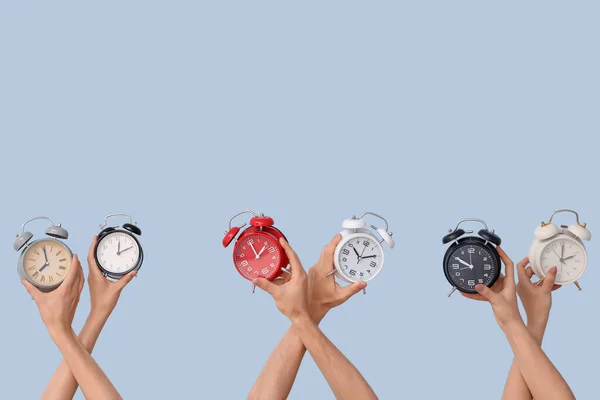 青い背景に異なる目覚まし時計を保持する手 — ストック写真