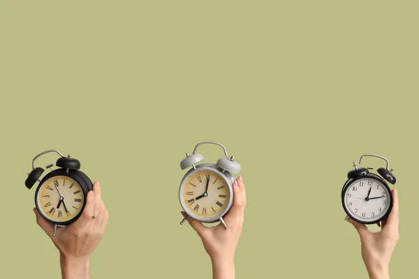 緑色の背景に異なる目覚まし時計を保持する手 — ストック写真