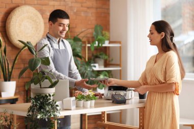 Çiçekçide dolar banknotlarıyla ödeme yapan genç bir kadın.