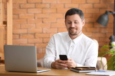 Ofiste akıllı telefonu olan bir iş adamı.