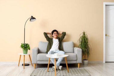 Genç Asyalı adam izin gününde evinde dinleniyor.