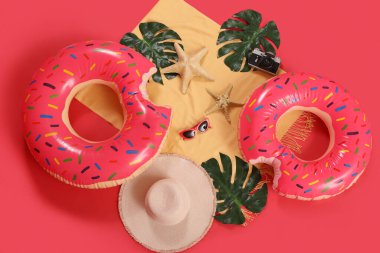 Kırmızı arka planda plaj aksesuarları olan şişme halkalar.