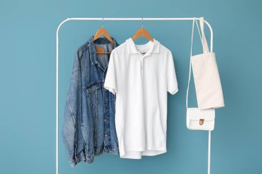 Renkli arka planda askıda asılı şık kıyafetler ve çantalar