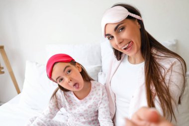 Mutlu anne ve yatak odasında uyuyan maskeli küçük kızı.