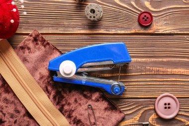 Kahverengi ahşap arka planda farklı malzemelerle elle dikiş makinesi.