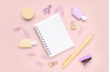 Pembe arka planda farklı kırtasiye malzemesi içeren defter.
