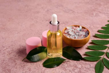 Pembe arka planda deniz tuzu bulunan şişe ve kozmetik ürünleri.