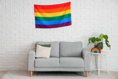 Oturma odasının içinde kanepe, masa ve asılmış LGBT bayrağı.