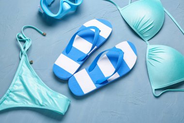 Grunge Blue arka planında plaj aksesuarları olan şık bayan terlikleri.