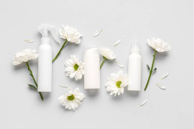 Kozmetik ürünleri ve gri arka planda papatya çiçekleri içeren kompozisyon