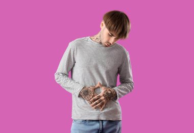 Mor arka planda karın ağrısı çeken genç bir adam.