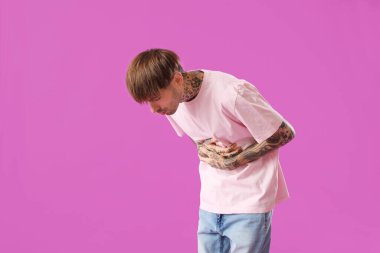 Mor arka planda karın ağrısı çeken genç bir adam.