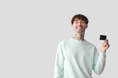 Kredi kartıyla dövmeli genç bir adam.