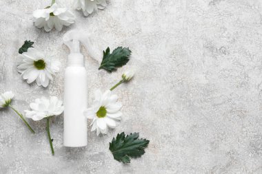 Kozmetik ürün şişesi ve arkaplanda papatya çiçekleri olan kompozisyon