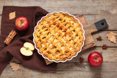 Lezzetli elmalı turta ve ahşap arka planda malzemelerle pişirme yemeği.