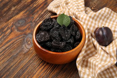 Ahşap arka planda lezzetli kurutulmuş erikli kase