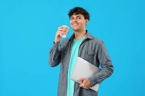 青い背景にコーヒーとラップトップのカップを持つ男性プログラマー — ストック写真