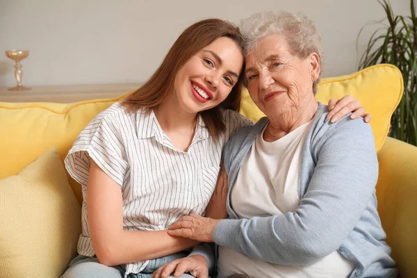 Young woman with her grandmother hugging at home