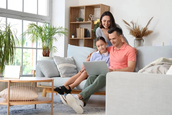 Happy family with laptop resting in living room