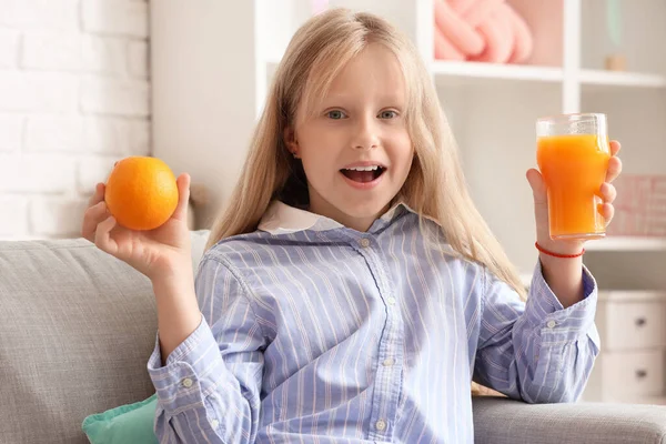 Evde meyve suyu ve portakallı küçük kız.
