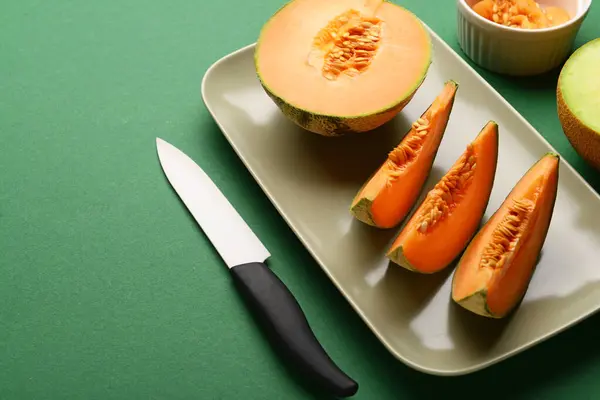 Plate with tasty ripe melon on green background