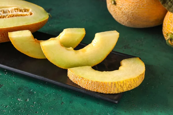 Board with pieces of sweet melon on green table