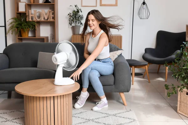 Young Woman Blowing Electric Fan Home — Stock Photo, Image