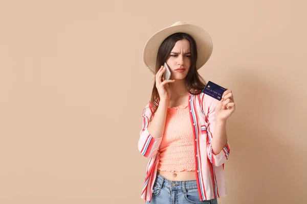 Беспокойная Молодая Женщина Кредитной Картой Разговаривает Мобильному Телефону Бежевом Фоне — стоковое фото