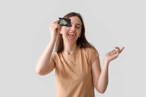 Молодая Женщина Кредитной Картой Показывает Язык Светлом Фоне — стоковое фото