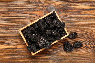 Ahşap zeminde lezzetli kurutulmuş eriklerle dolu bir kutu.