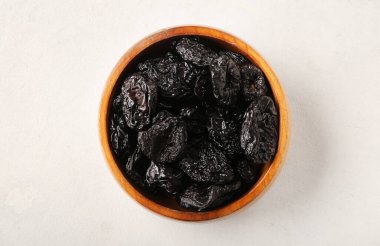 Beyaz zemin üzerine lezzetli kurutulmuş Erik ile kase