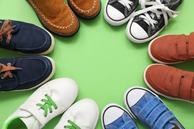Yeşil arka planda farklı çocukların ayakkabılarından yapılmış çerçeve, yakın plan