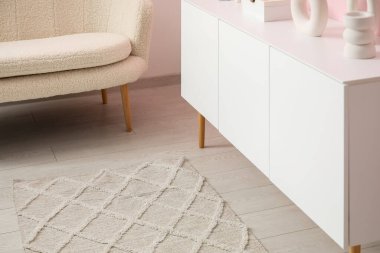 Şık halısı, kanepesi ve beyaz büfesi olan oturma odasının içinde.