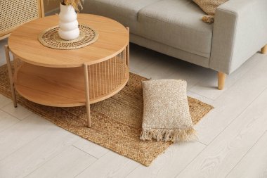 İçinde hasır halı, ahşap sehpa ve gri kanepe olan oturma odası.