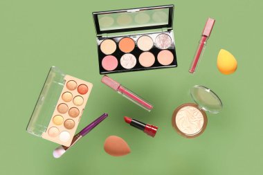 Yeşil arka planda uçan dekoratif kozmetik ürünleri