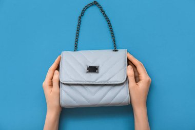 Renkli arka planda zarif mavi zincir çantalı kadın eli