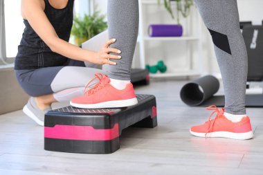 Rehabilitasyon merkezinde stepper ve terapistle olgun kadın eğitimi, yakın çekim.