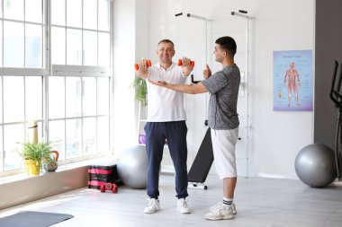 Rehabilitasyon merkezinde dambılı ve terapisti olan olgun bir adam eğitimi.