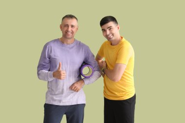 Yeşil arka planda köpük silindirli olgun bir adam ve rehabilitasyon terapisti.