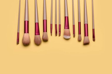 Sarı arkaplanda makyaj fırçaları