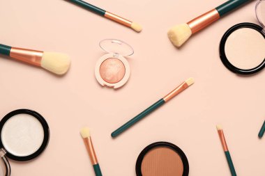 Pembe arka planda makyaj fırçaları ve farklı dekoratif kozmetikler