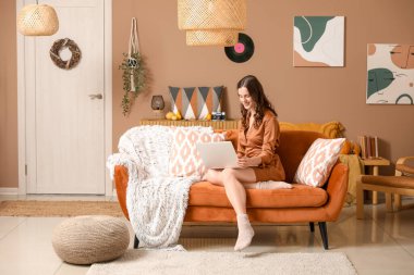 Sonbahar günü evde dizüstü bilgisayar kullanan genç bir kadın.