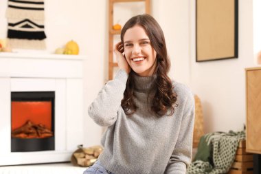 Sonbahar günü evde gülümseyen genç kadın.