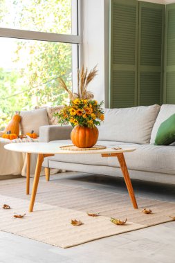 Oturma odasındaki masada sonbahar çiçekli balkabağı.